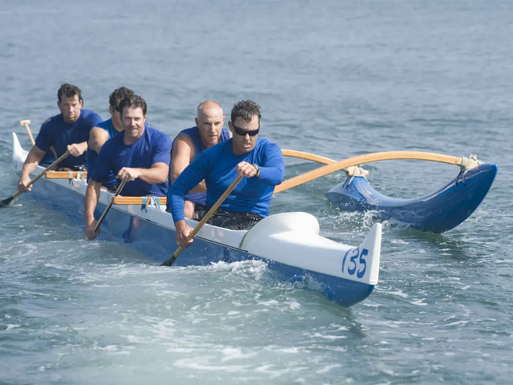 Five men racing an outrigger canoe