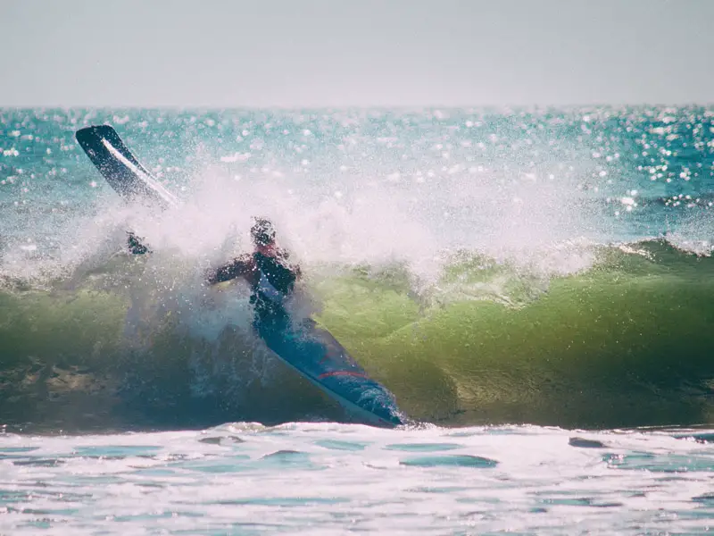 A kayaker dangerously paddling through breaking surf. 