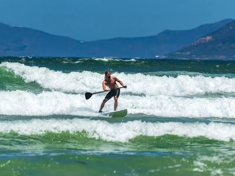 A man surfing on a stand up paddle board