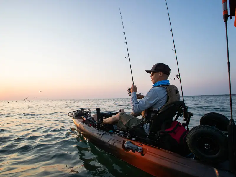 A man sitting in a sit-on kayak while fishing.