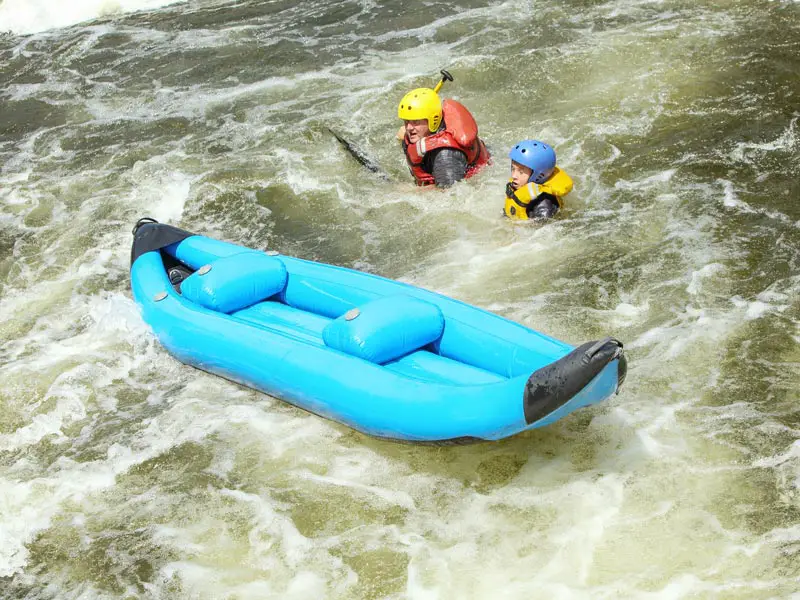 Two people falling out of a canoe in white water