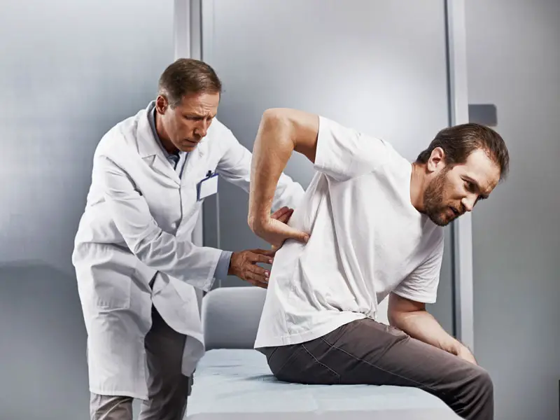 An image showing a doctor examining a patients sore back.