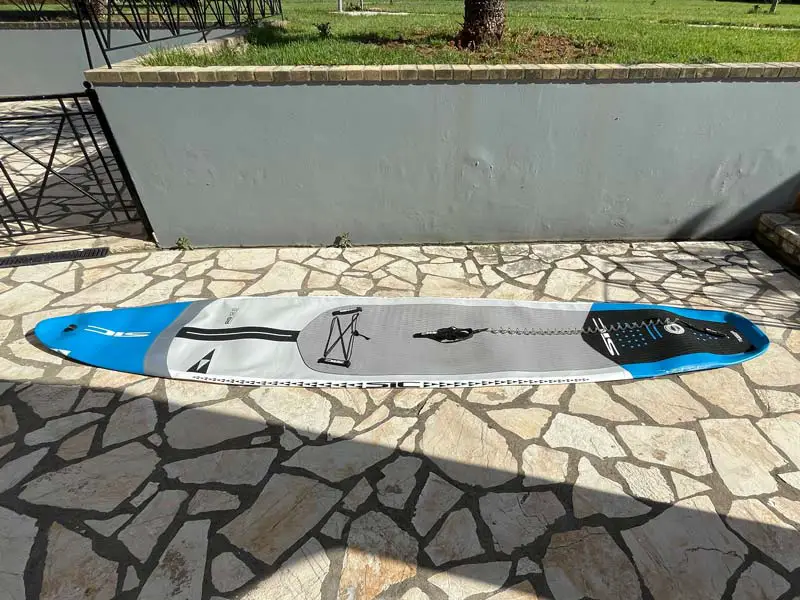 A fully deflated paddle board lying on the ground.