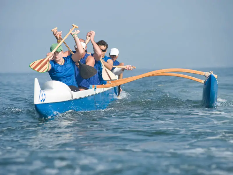Four men paddling an outrigger canoe.