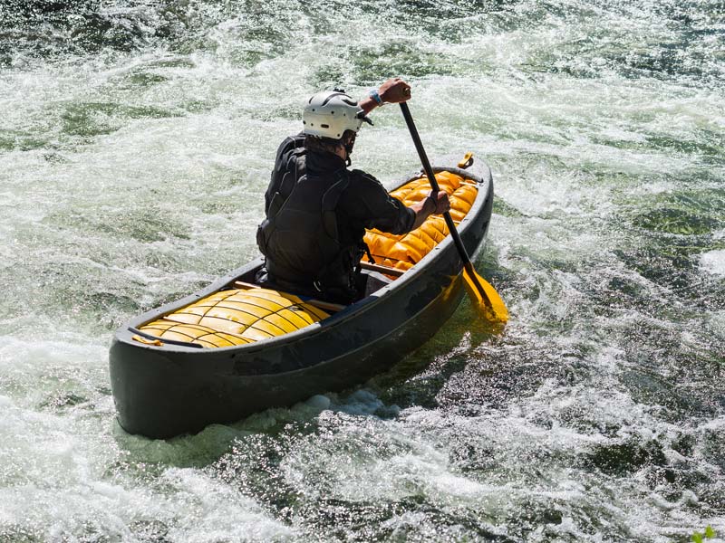 A person paddling a white water canoe down river rapids